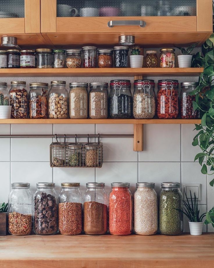 Glass jars of whole grains, legumes, nuts, and seeds arranged on a pantry shelf